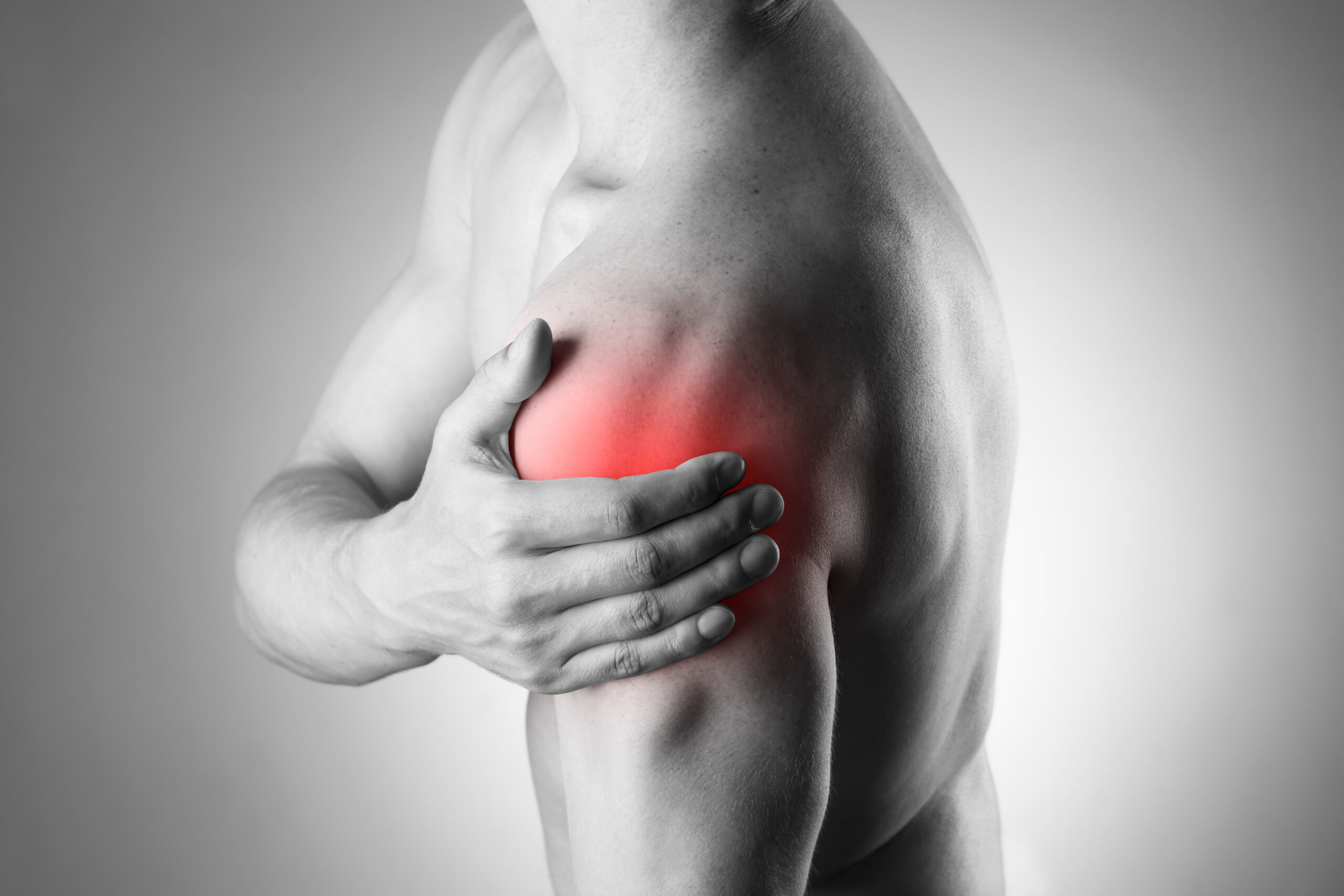 Man with pain in shoulder. Pain in the human body. Black and white photo with red dot